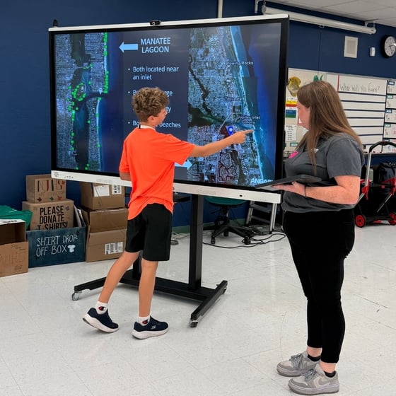 ANGARI staff working with a student on a smartboard during a Lagoon Drift school visit.